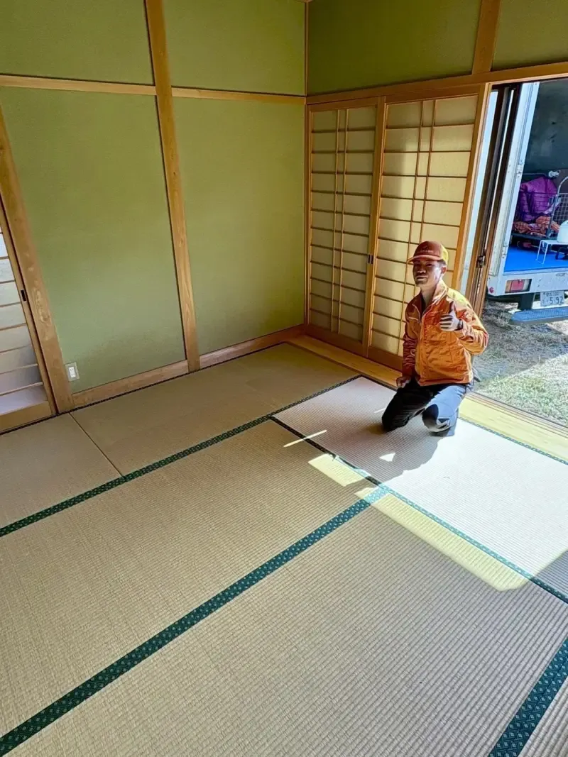 荷物を運び出して畳だけになった作業後の和室と、掃き出し窓の外に停めた回収トラック