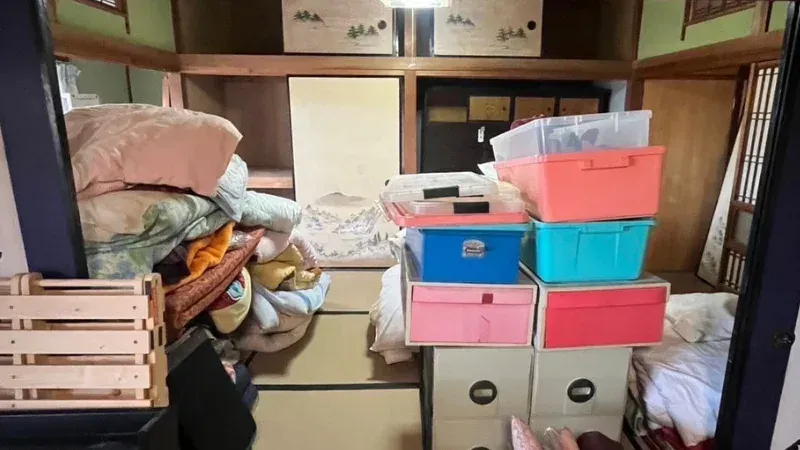高松市Y様宅の片付け前のお部屋に積まれた布団や衣装ケース